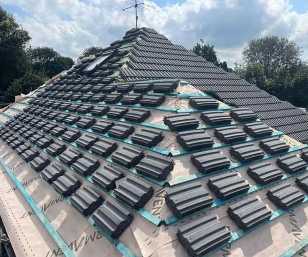 This is a photo of a new hip roof being installed. New felt, battens, and grey tiles have been installed, also a new velux window. Works carried out by ATC Roofing Bromham