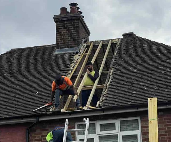 This is a photo of a roof repair being carried out. A section of the roof has been stripped and two roofers are replacing the rafters. Works being carried out by ATC Roofing Bromham